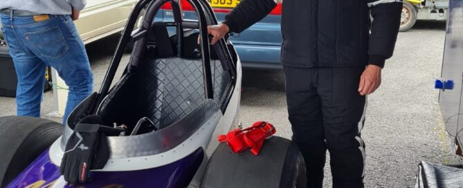 Wayne Colliver stood next to a Nostalgia Nationals car with a helmet on