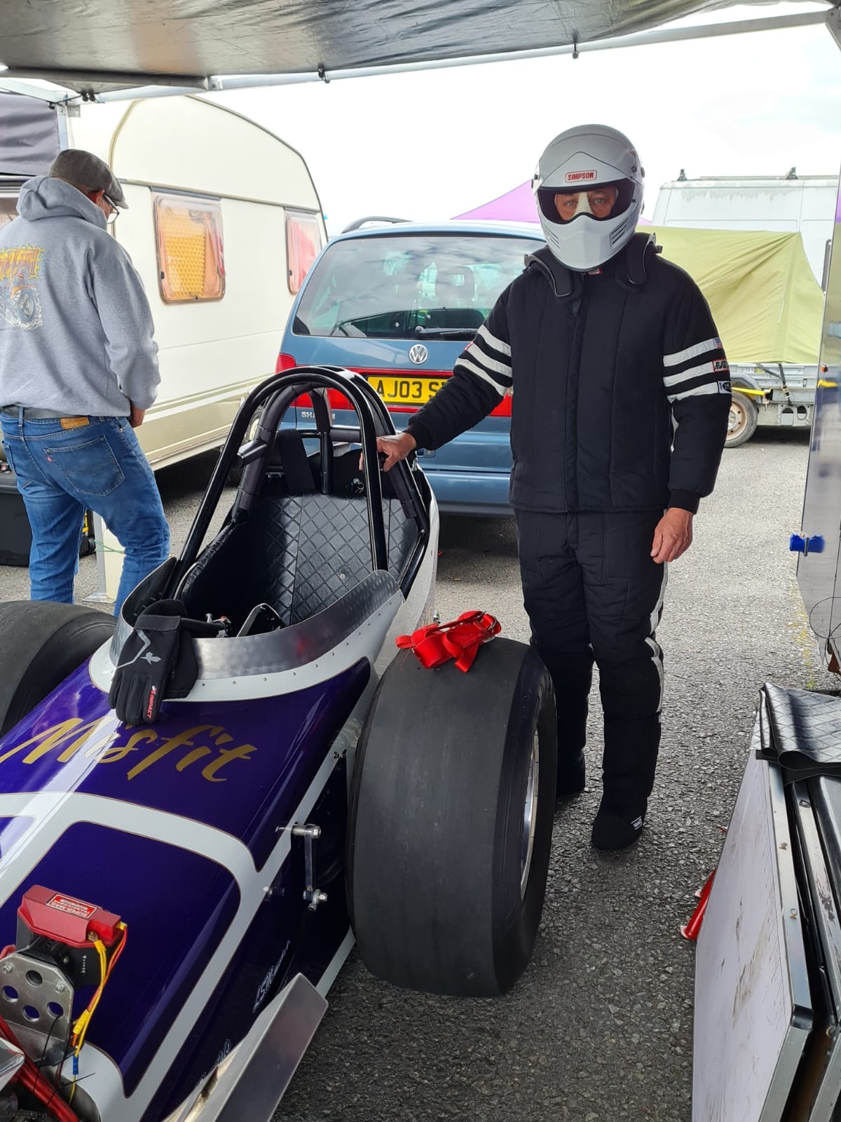 Wayne Colliver stood next to a Nostalgia Nationals car with a helmet on